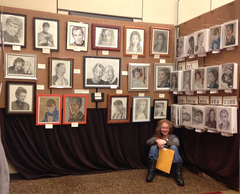 Artist Guest of Honor Lori Del Genis in front of a display of her work at Arisia 2017
